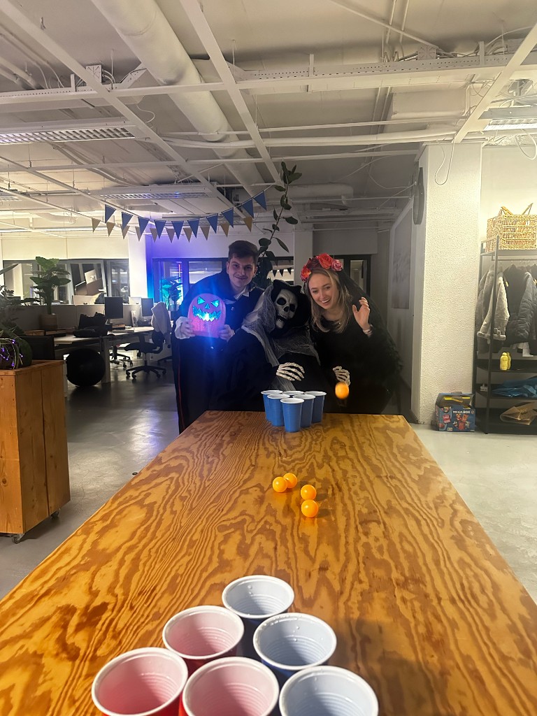 ChannelDock team in Halloween costumes playing beer pong in the office